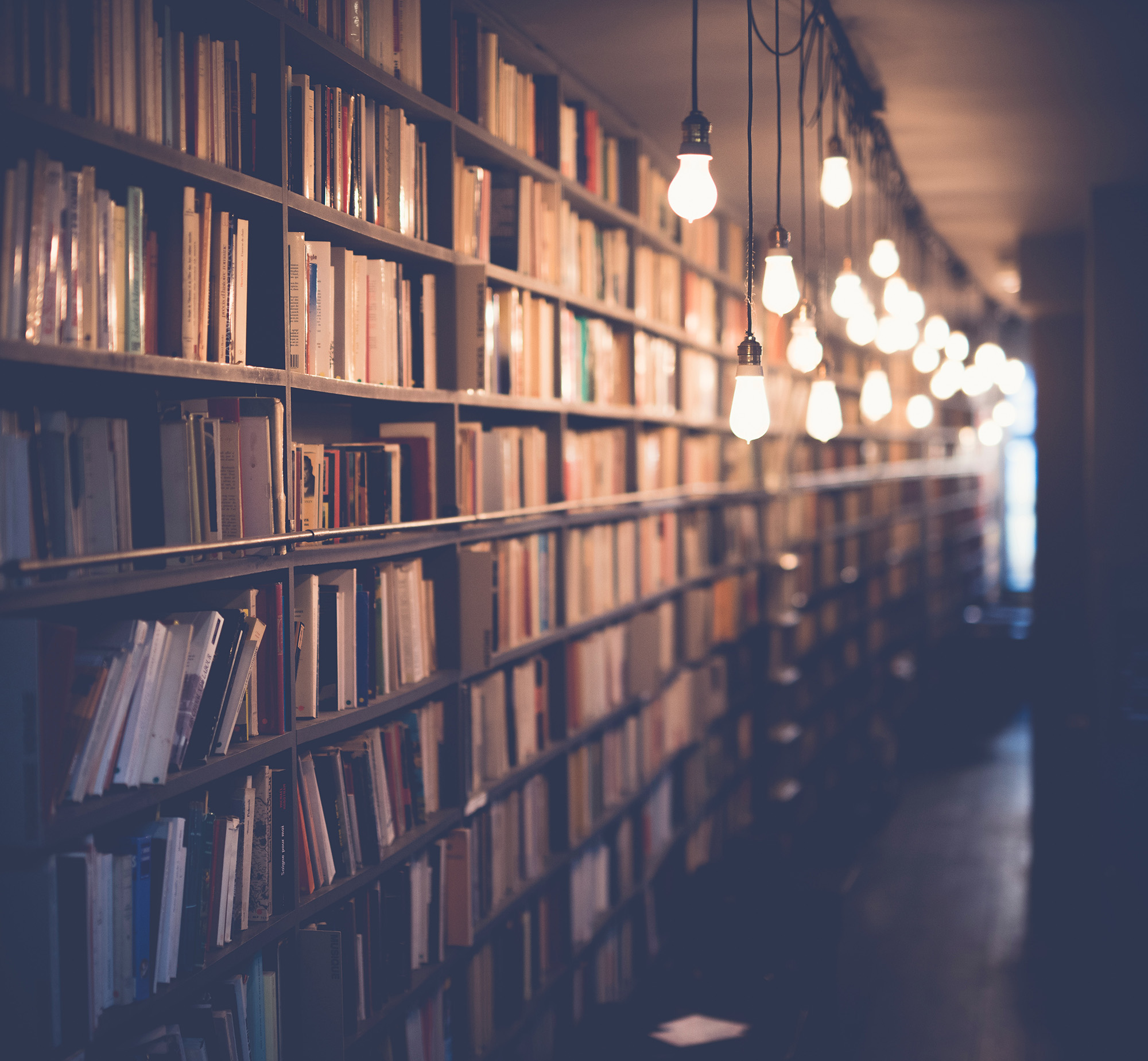 Image of books on shelves in a dimly lit library