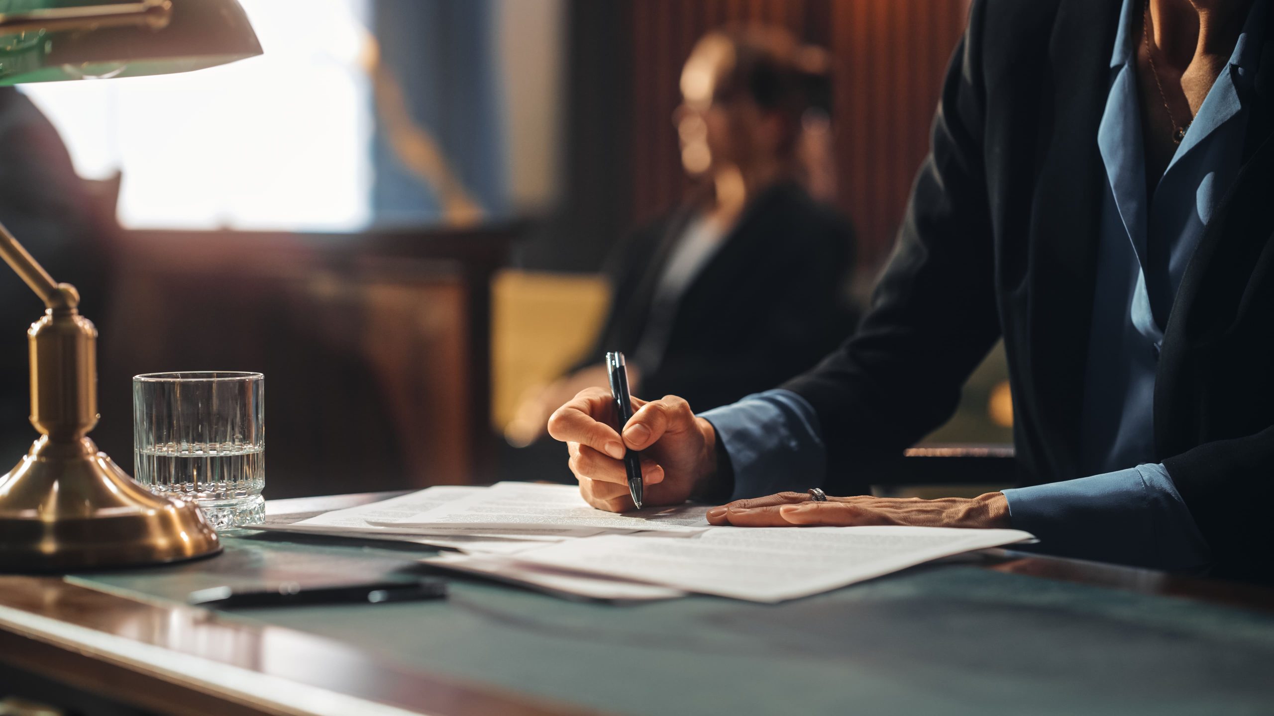Image of a hand holding pen and signing paperwork
