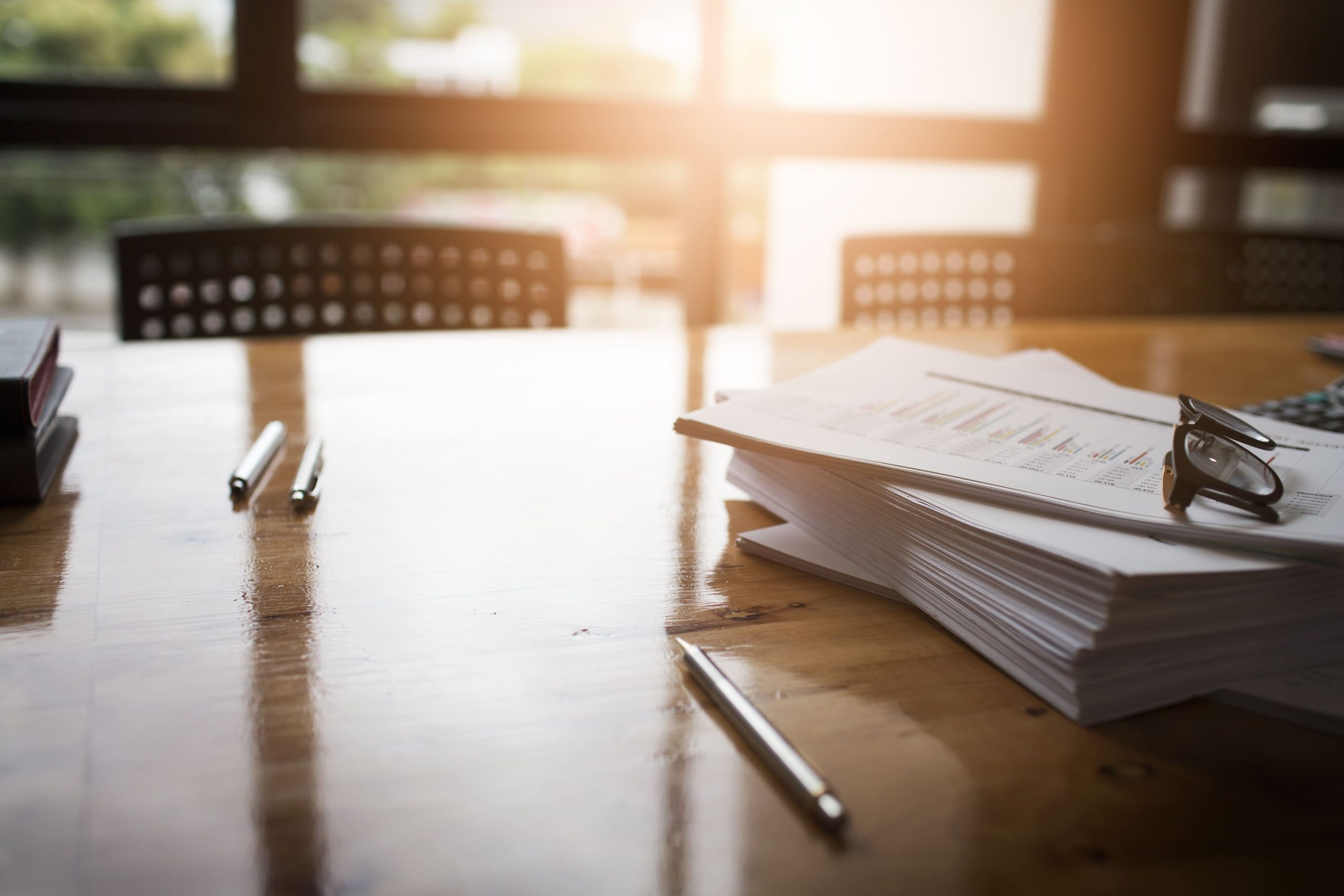 Image of a stack of documents with reading glasses and stationery